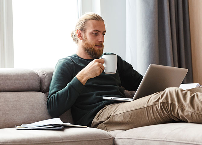 man working on laptop and drinking coffee