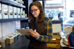 Coffee retail worker doing inventory while holding a tablet.