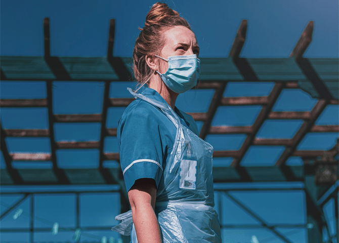 A nurse stands against the sky and looks into the distance