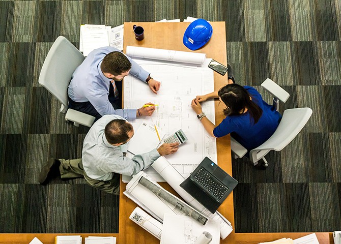 Hiring team reviewing blueprints and planning materials around a table, illustrating workforce planning and scalable hiring.